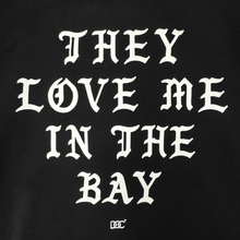 Load image into Gallery viewer, White Gothic-style text on a black background reads: “THEY LOVE ME IN THE BAY.” Centered beneath the statement, a small decorative By DOC logo enhances the classic streetwear aesthetic. Crafted as part of The Bay Collection, the They Love Me Zip By Doc from By DOC delivers iconic style to your wardrobe—perfect for layering with your favorite heavyweight fleece or zip-up hoodie.